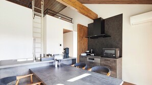 Una cocina moderna con estufa, horno y microondas integrados. Se observa una escalera de madera y una encimera blanca.