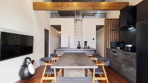 Una cocina moderna con una isla grande, vigas de madera y un televisor de pantalla plana montado en la pared.
