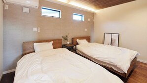 Una habitación de hotel con dos camas individuales, una mesita de noche pequeña con una lámpara y un aire acondicionado instalado en la pared.