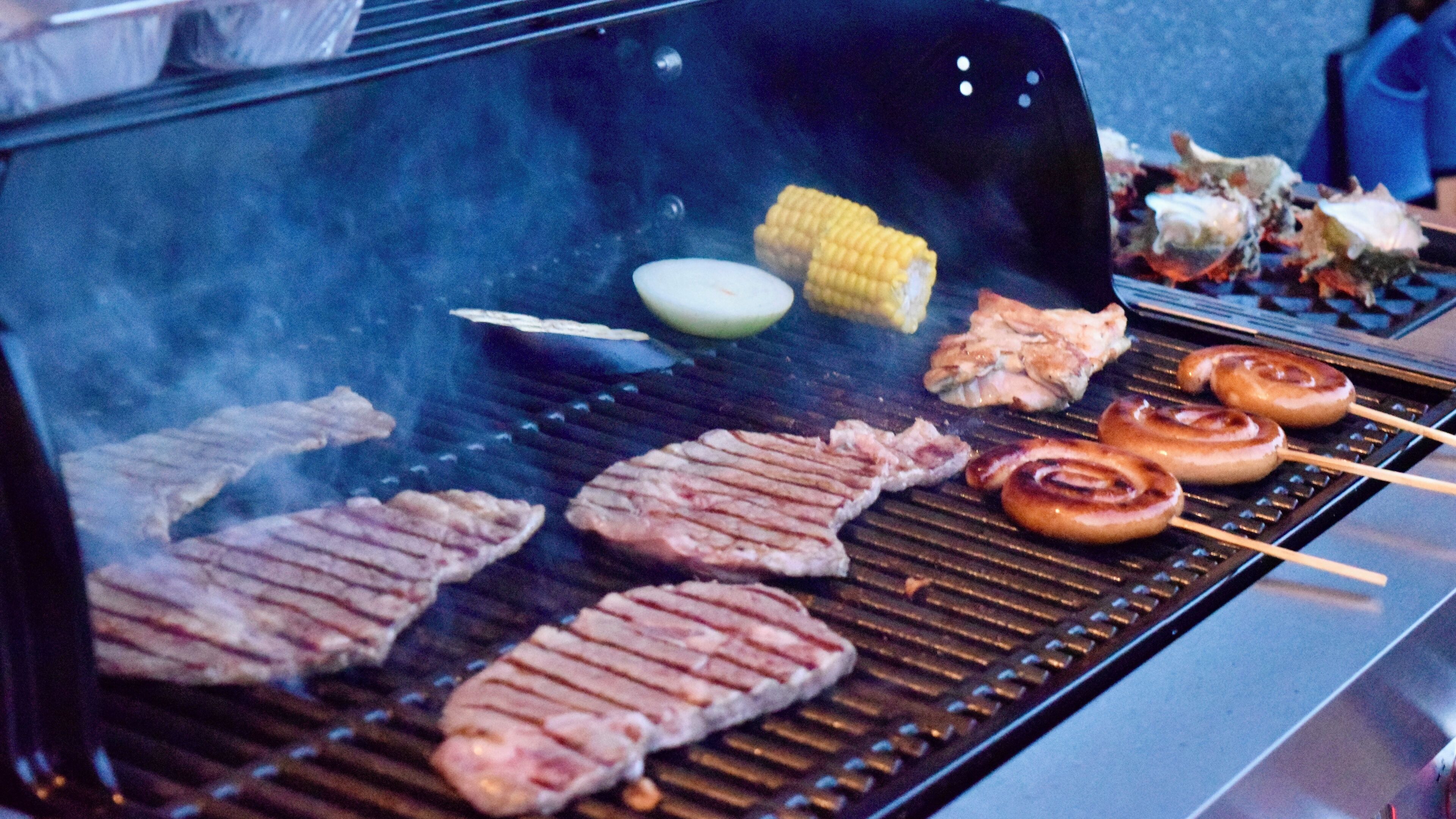 En grill med olika sorters kött och grönsaker som tillagas.