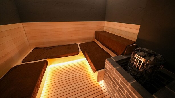 A sauna room with wooden benches and a stone fireplace. - Solution Cube Tokuyama (Shunan)