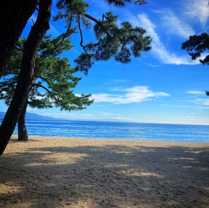 A beach with clear blue water and a sandy shore, surrounded by trees. - Sumotoya (Sumoto)
