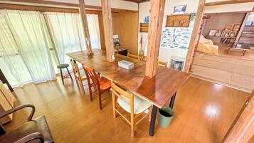 Un comedor con una mesa y sillas de madera, techo de madera y vista al mar a través de una ventana.