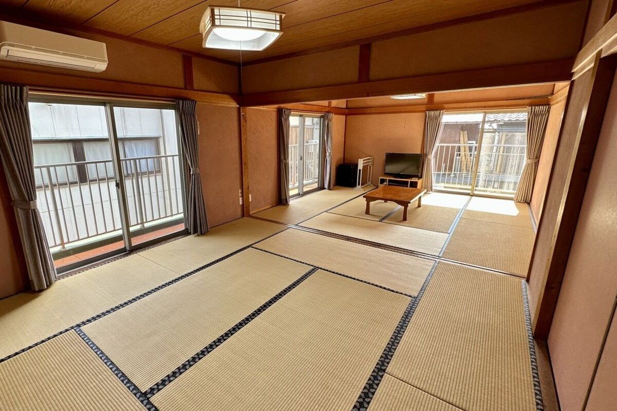 A tatami mat room with sliding doors, a television, and a small table.