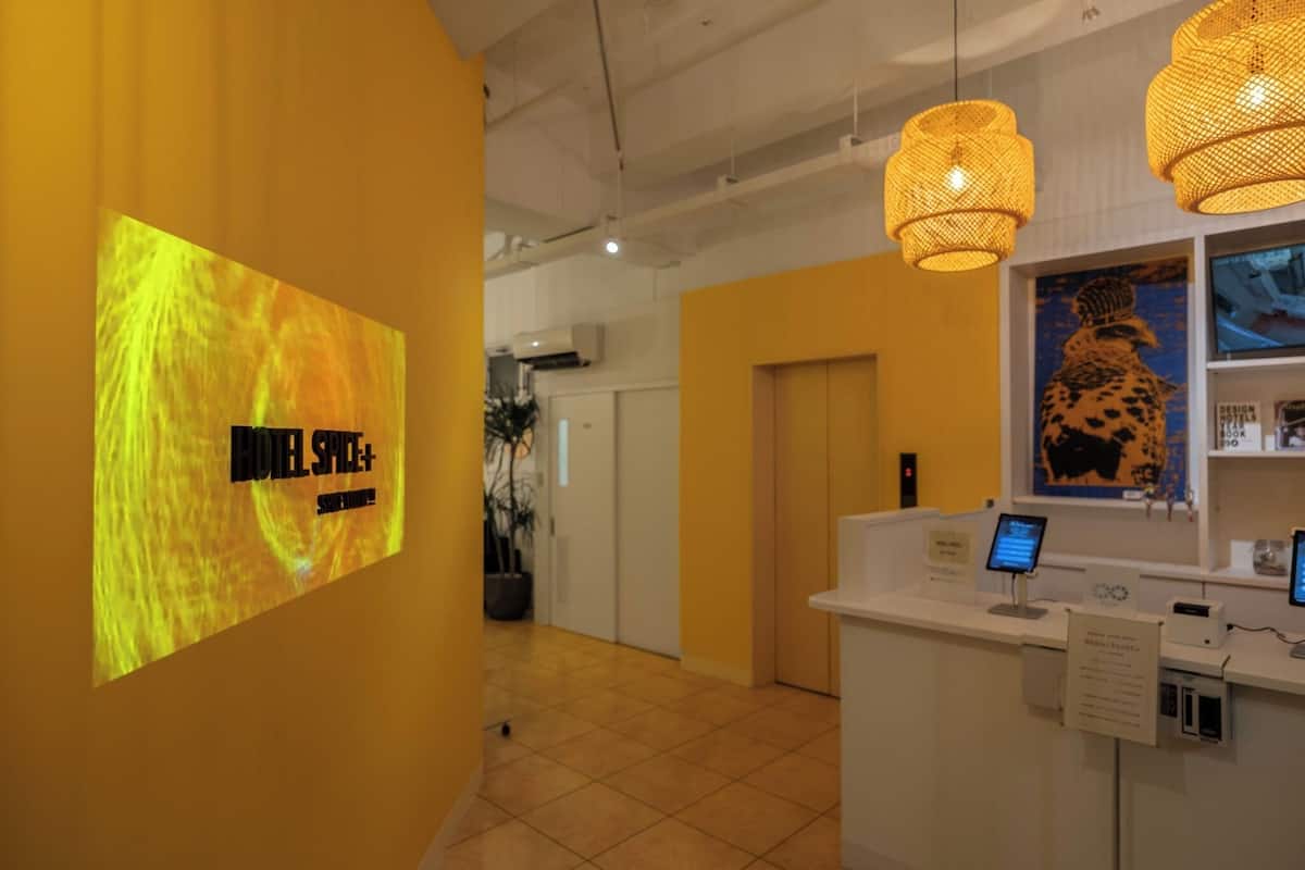 A reception area with a digital display, a reception desk, and a large poster on the wall.