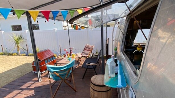 An outdoor patio area with a covered seating arrangement, a bar counter, and a large window. - Ichinomiya Base 73 (Ichinomiya)