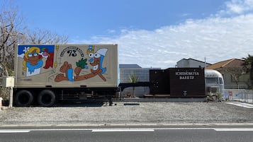 Un camion orné d’une publicité colorée est garé devant un bâtiment portant l’inscription « ICHINOMIYA BASE 73 ».