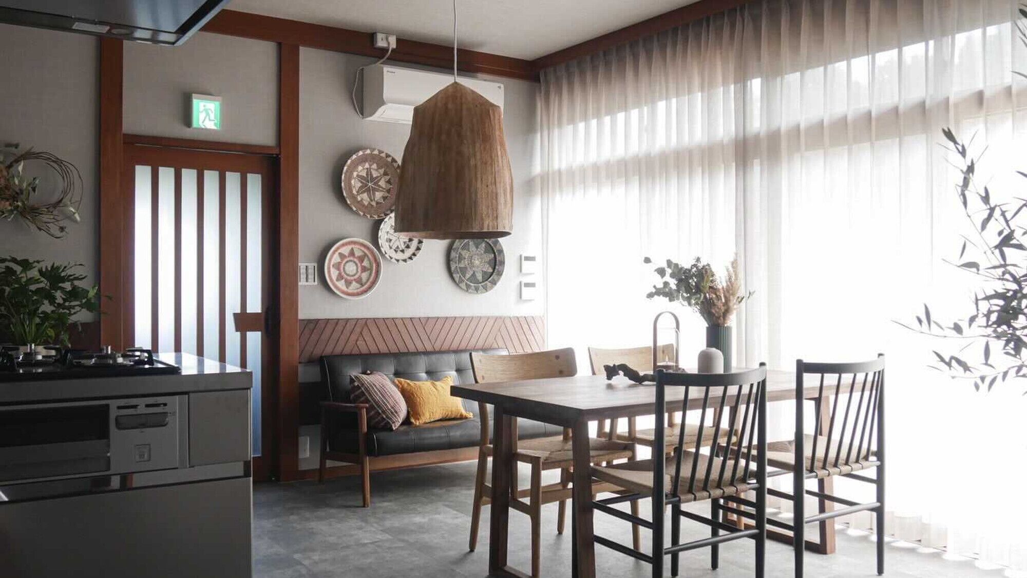 Une cuisine moderne avec un coin repas, comprenant une table en bois, des chaises et un luminaire suspendu.