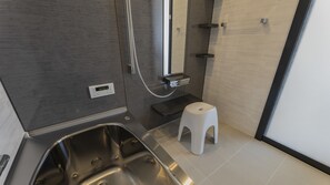 A modern bathroom with a stainless steel sink, a small white stool, and a shower area. - Doggywood Awaji Island (Awaji)