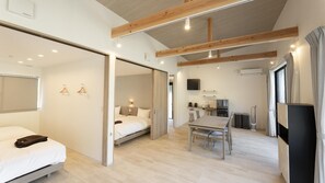 A modern hotel room with a bed, a desk, and a kitchenette.