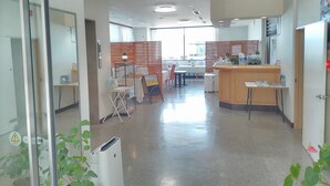 Un hall d’hôtel comprenant un comptoir d’accueil, un espace salon et une grande fenêtre laissant entrer la lumière naturelle.