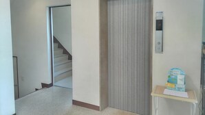 Un couloir avec un escalier, une porte et une petite table sur laquelle se trouvent une boîte de mouchoirs et des mouchoirs.