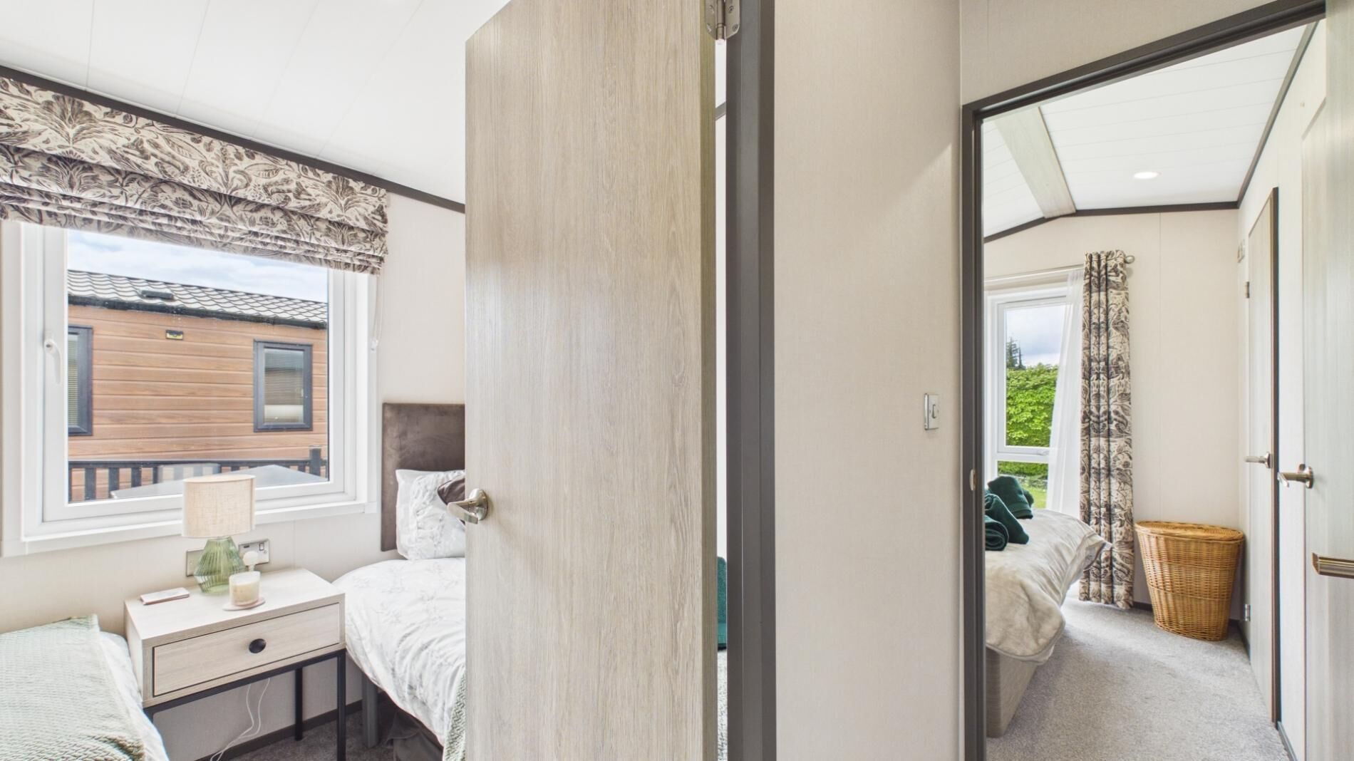 Un dormitorio con cama, mesita de noche, lámpara y ventana con cortinas.