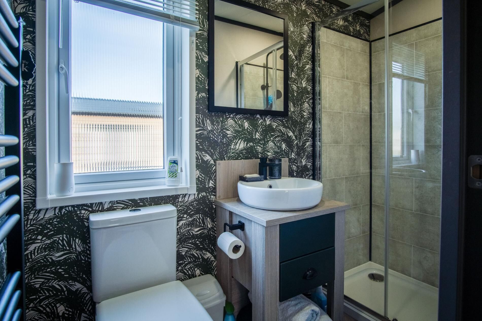 A bathroom with a toilet, a sink, a shower, and a window.