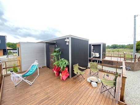 A deck with a hammock, chairs, and potted plants.