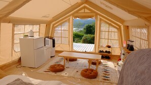 Een knus tent-achtig verblijf met een kitchenette, een tafel en uitzicht op de omgeving.