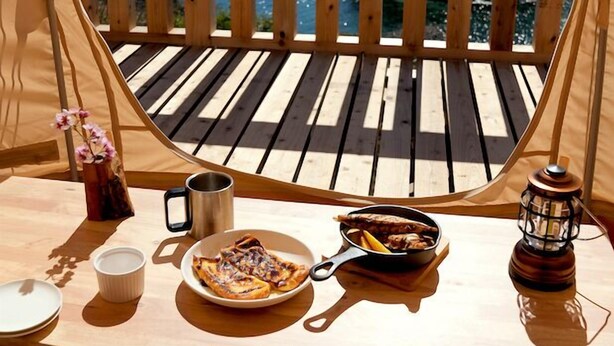 Een houten terras met een gedekte tafel, met uitzicht op een waterpartij.