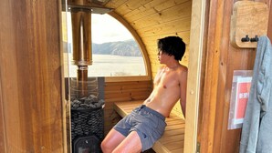 Een sauna met houten wanden, een sauna-oven en uitzicht op het omliggende landschap.