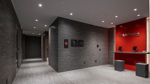 A modern hotel lobby with a dark grey wall, a red accent wall, and a reception desk. - Hotel R9 Premium Ichikawa Ekimae (Ichikawa)