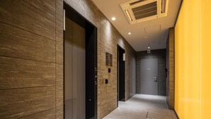 A modern hallway with a marble wall, a door with a sign, and a vent on the ceiling. - Hotel R9 Premium Ichikawa Ekimae (Ichikawa)