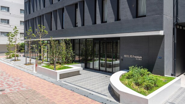 A modern hotel entrance with a dark facade, large glass doors, and a sign indicating it's a premium hotel. - Hotel R9 Premium Ichikawa Ekimae (Ichikawa)
