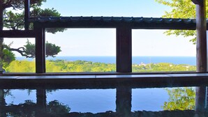 Vista dalla finestra che riflette chiaramente il cielo e il mare, immersa nel verde.