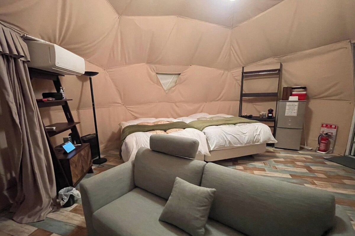 A cozy room with a bed, a sofa, a small table, and a shelf.