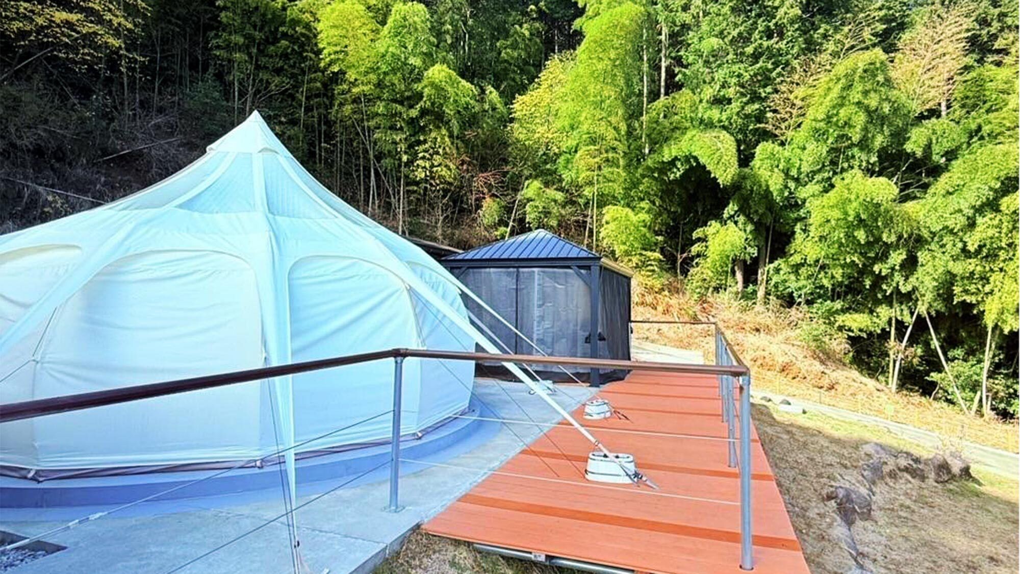 Una tenda e una piccola costruzione in una zona boschiva.