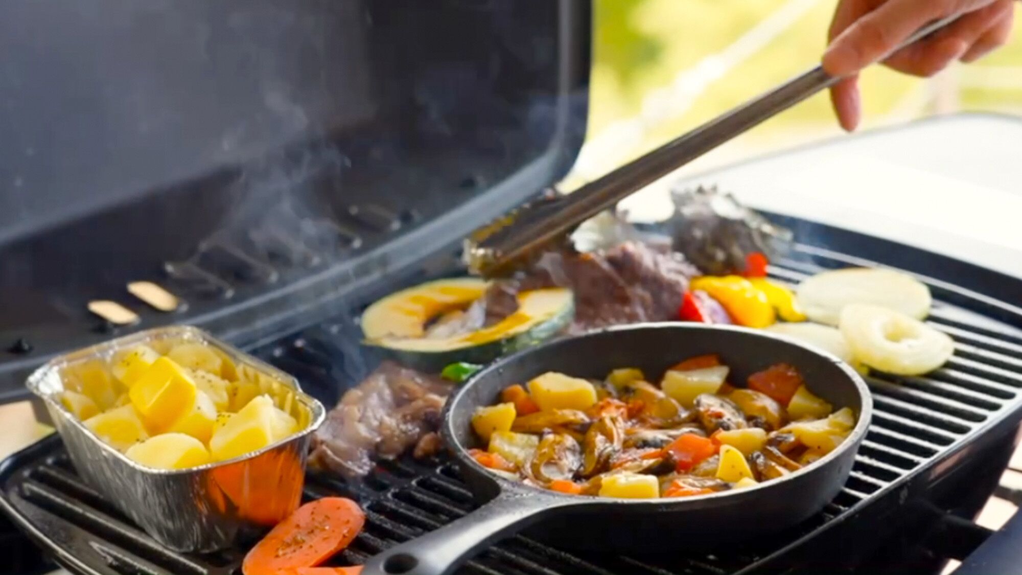 A grill with various foods being cooked, including sausages, vegetables, and meat.