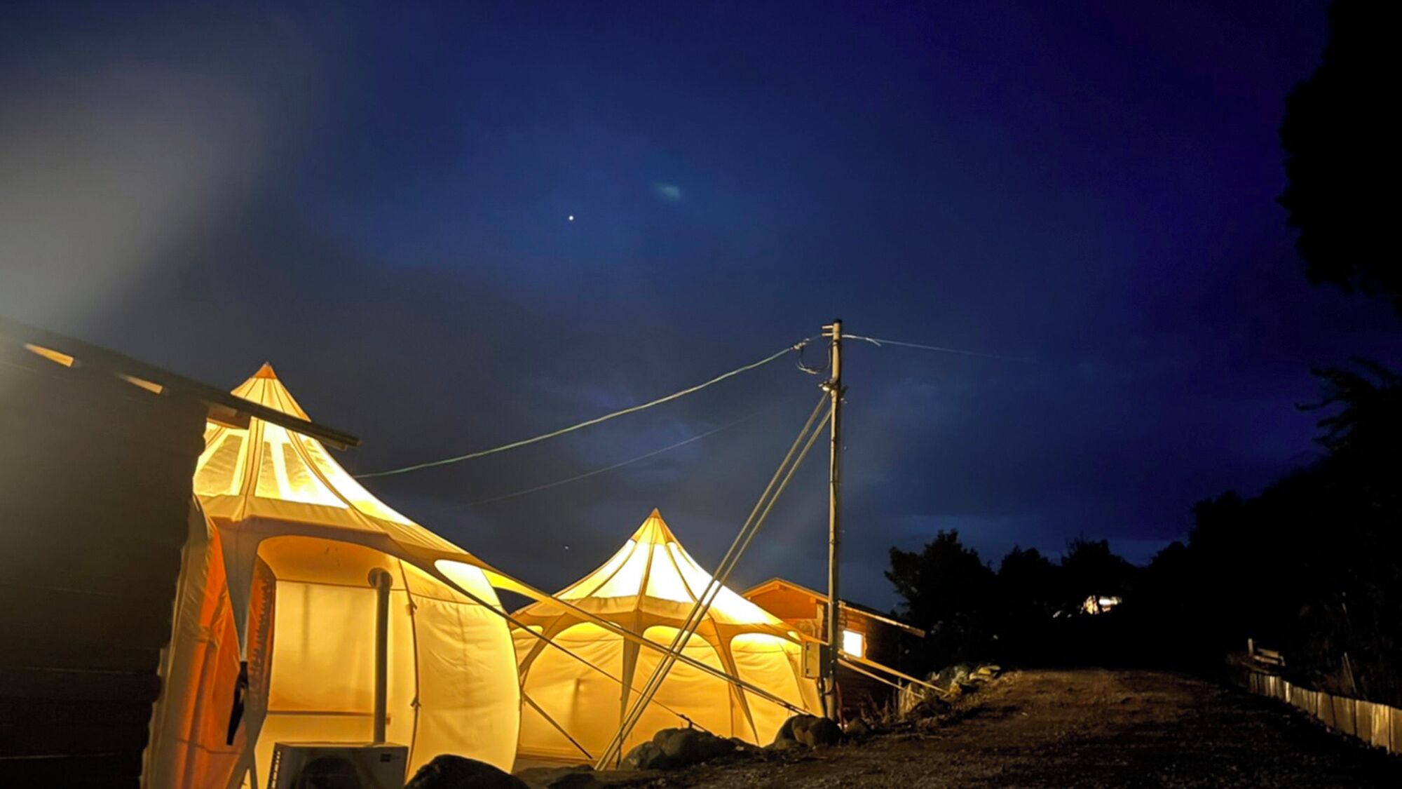 A row of tents with a power line and a utility pole in the background.