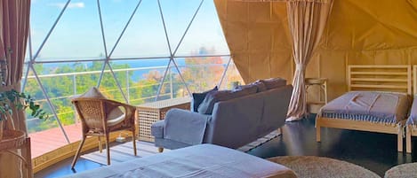 Una habitación acogedora con un ventanal grande, un sofá, una cama y una silla.