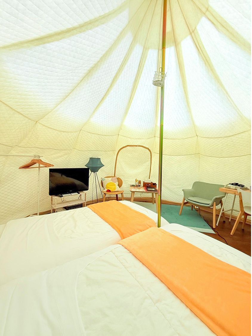 Una carpa con cama, una silla, una mesa y una lámpara.