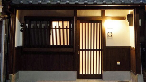 En traditionell japansk entré med en träport och skjutdörrar.