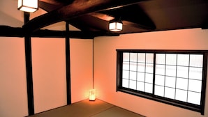Ett traditionellt japanskt rum med tatamimattor på golvet, ett skjutbart fönster av rispapper (shoji) och en hängande papperslykta.