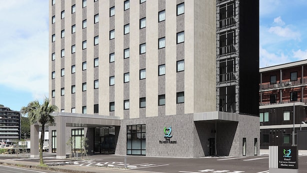 Ein modernes Hotelgebäude mit auffälligem Logo an der Fassade, zahlreichen Fenstern und einem Flachdach.