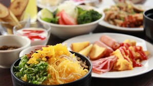 A variety of dishes including shredded cheese, sliced ham, and vegetables on a table. - Hotel Yui-ness-amami Marine Town (Amami)