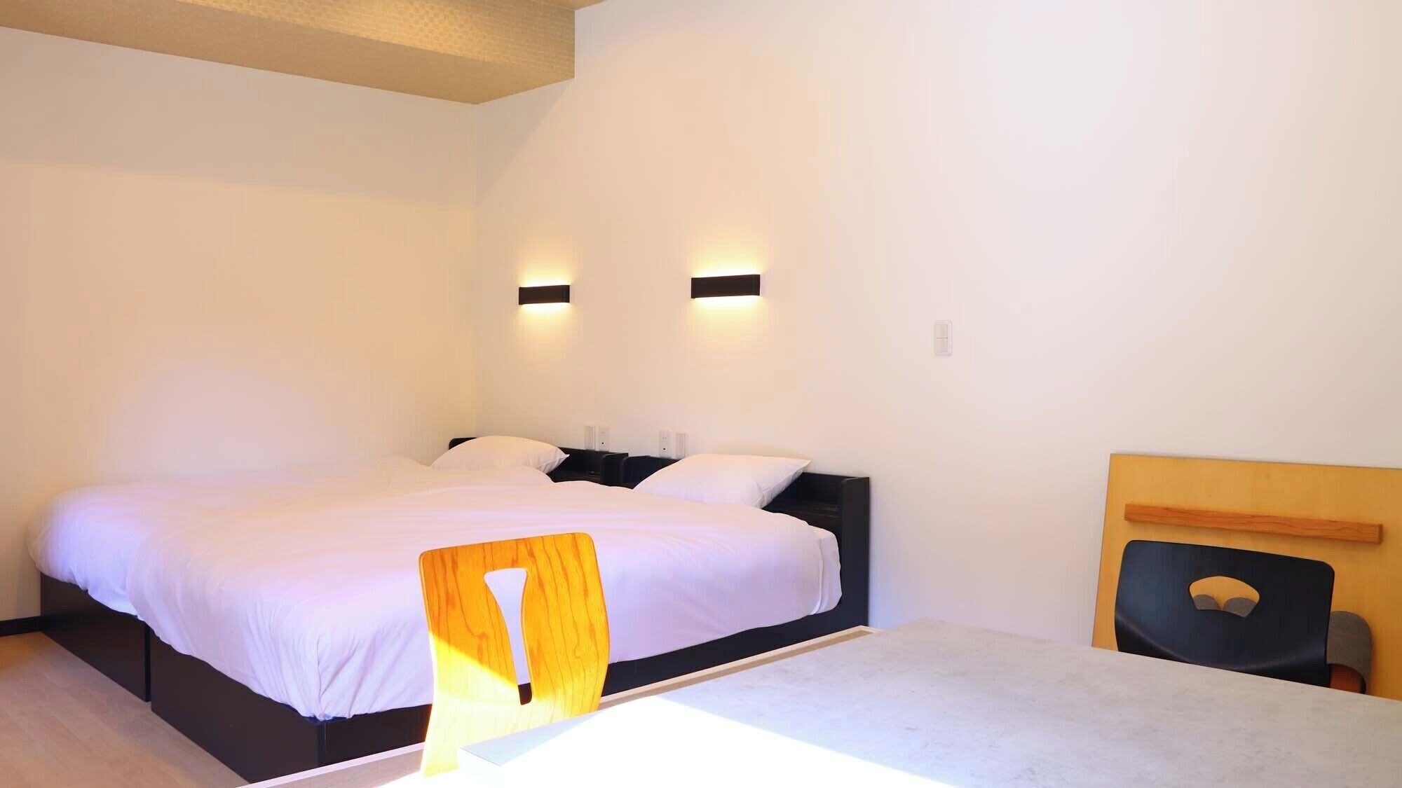 A bedroom with a large bed, two bedside tables, a chair, and a small table.