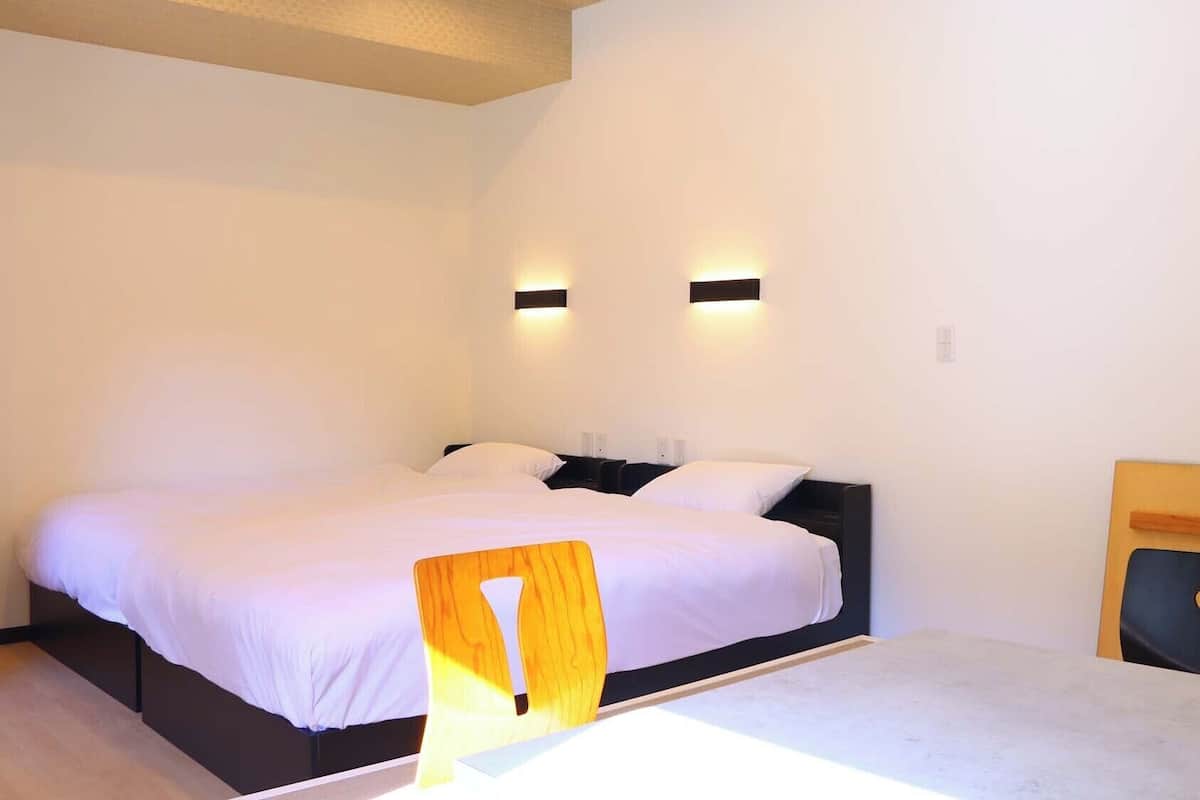 A bedroom with a large bed, two bedside tables, a chair, and a small table.