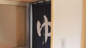 A room with a sliding door leading to a dark room with a white geometric design on the door. - Tamayama Onsen Tamaya Ryokan (Iwaki)
