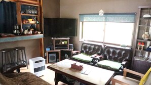 Un salon avec un canapé marron, une table basse en bois, un téléviseur et une fenêtre avec des stores.