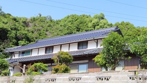 Un bâtiment japonais traditionnel, avec un toit recouvert de tuiles, des poutres en bois et une base en pierre.