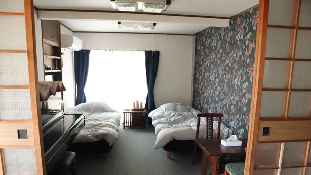 Une chambre de taille modeste, comprenant deux lits, une petite table et une chaise.