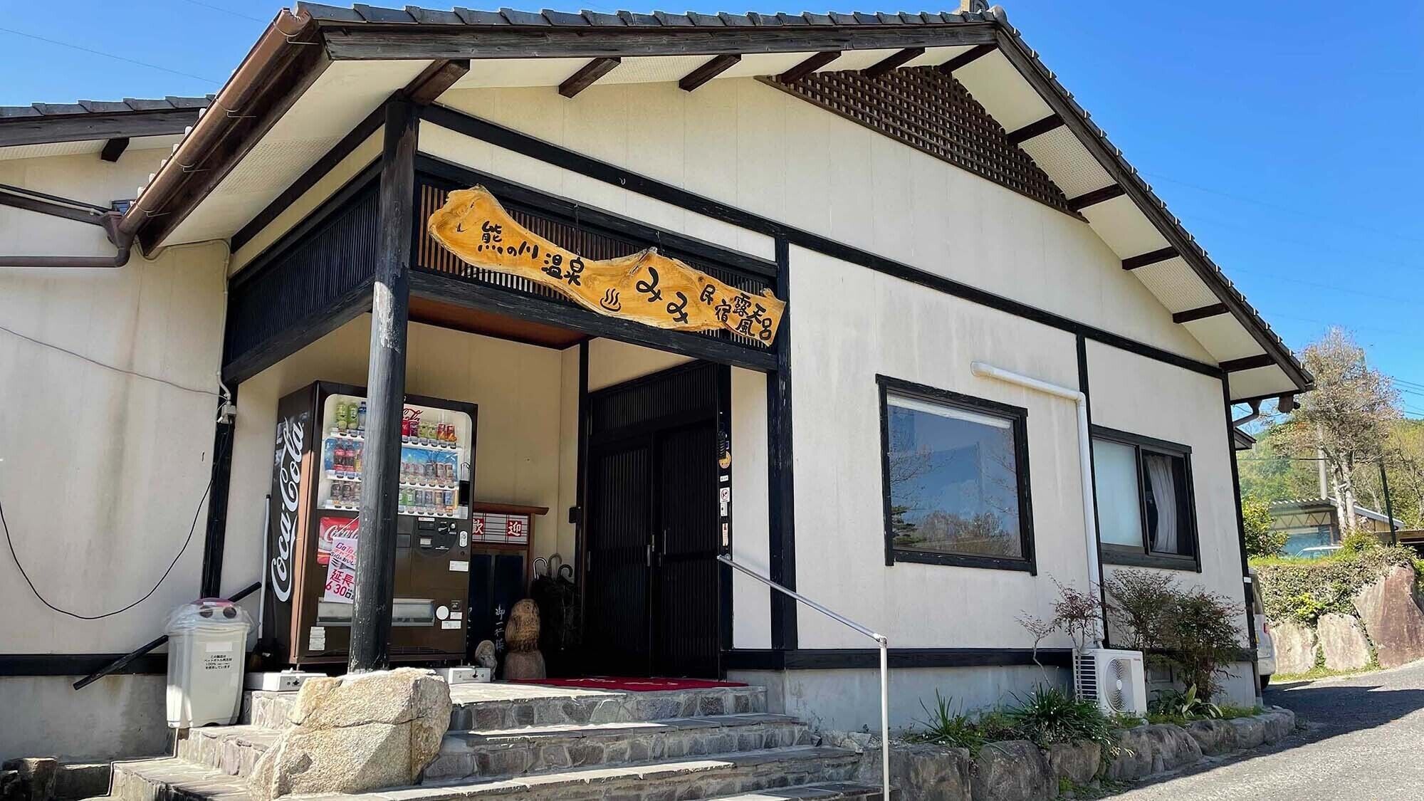 A traditional Japanese building with a wooden entrance and a signboard.