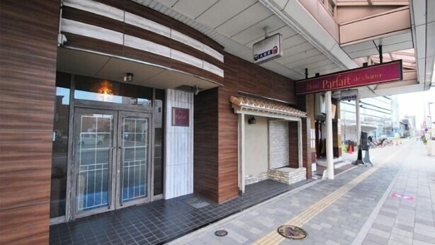 A hotel entrance with a glass door, a sign for 'Hotel Parfait de Chiemsee', and a covered walkway. - Hotel Parfait de Charme (Ichinomiya)