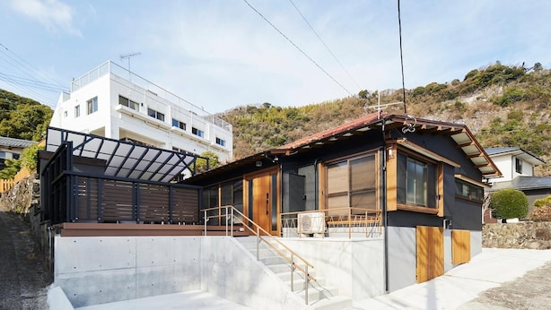 A modern house with a wooden deck, large windows, and a concrete staircase. - Maigre Uminokoe (Ito)