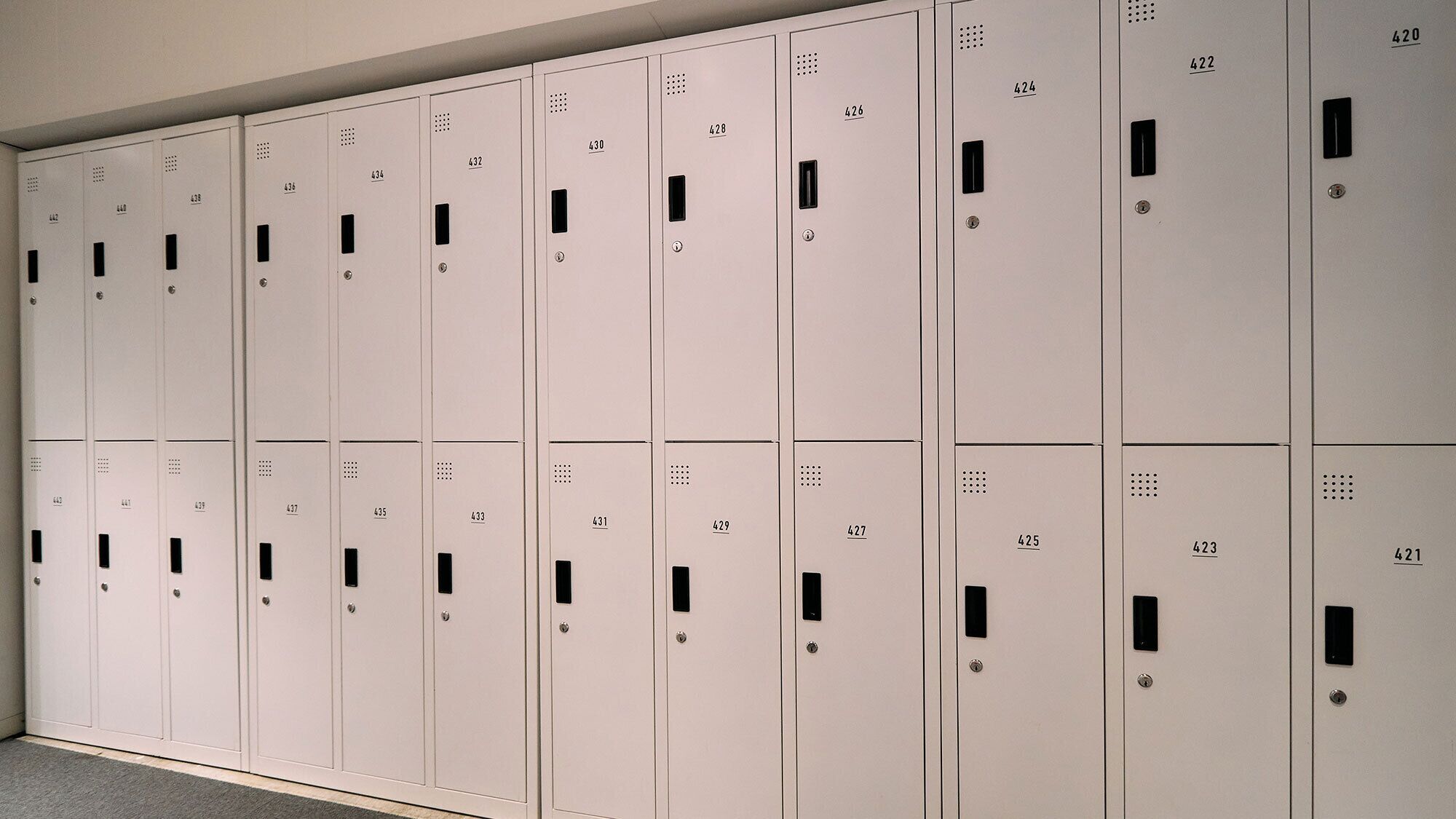 A row of white lockers with numbers on them, likely used for storing personal items.