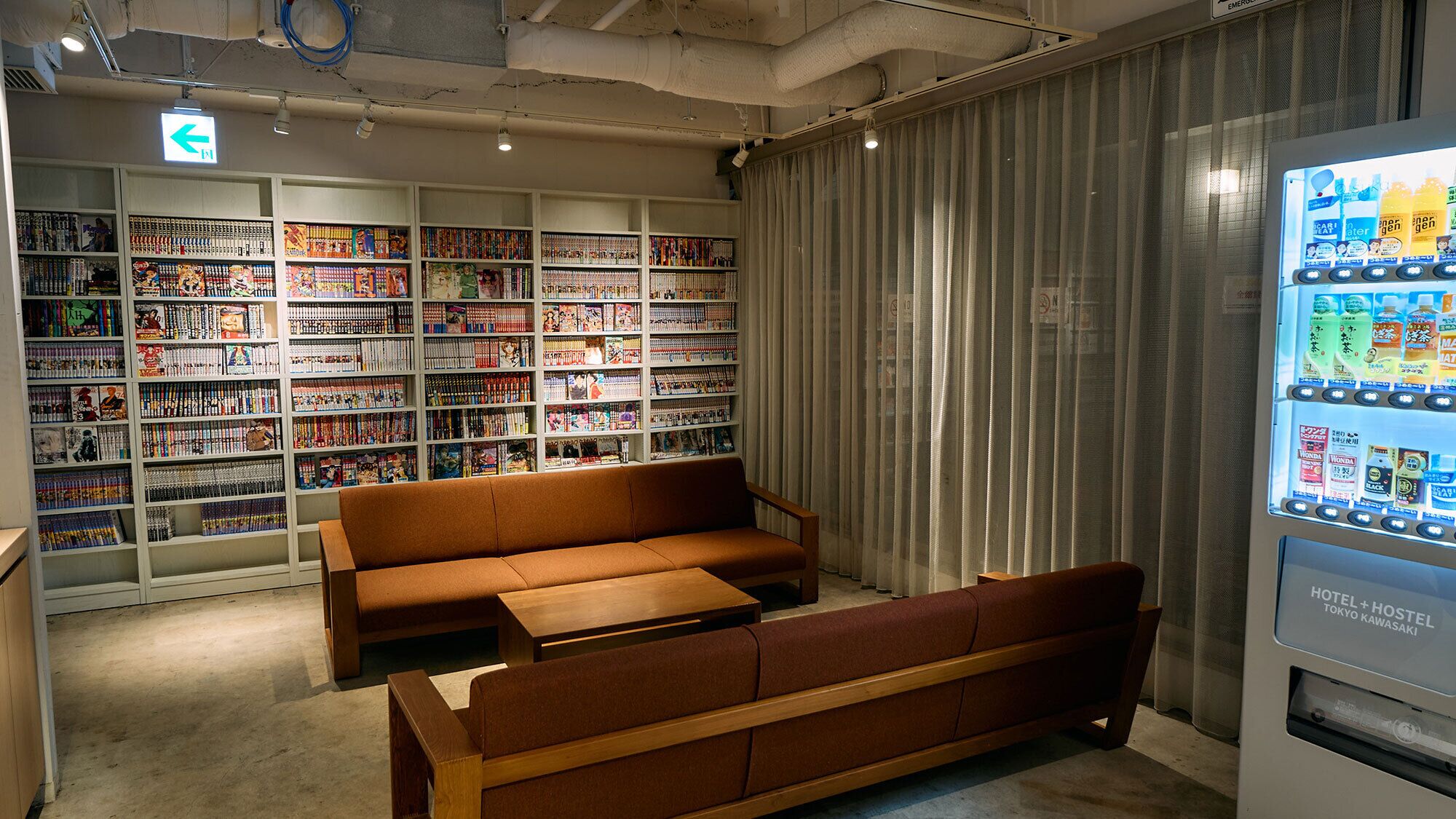Een bibliotheek met boekenkasten, een bruine bank en een automaat.