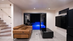 Een moderne woonkamer met een bank, een flatscreen televisie en een trap.