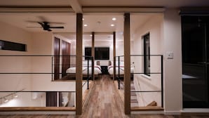 Een hotelkamer met een houten vloer, een plafondventilator en een raam.