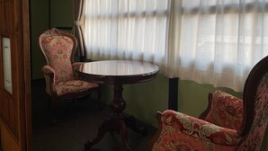 Una habitación con una mesa redonda de madera y dos sillas decoradas con tapicería floral.